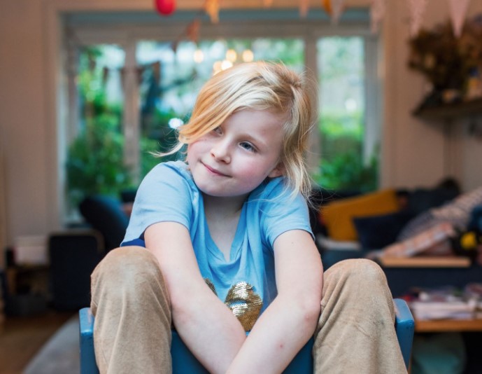 Jong meisje zittend op stoel in de woonkamer