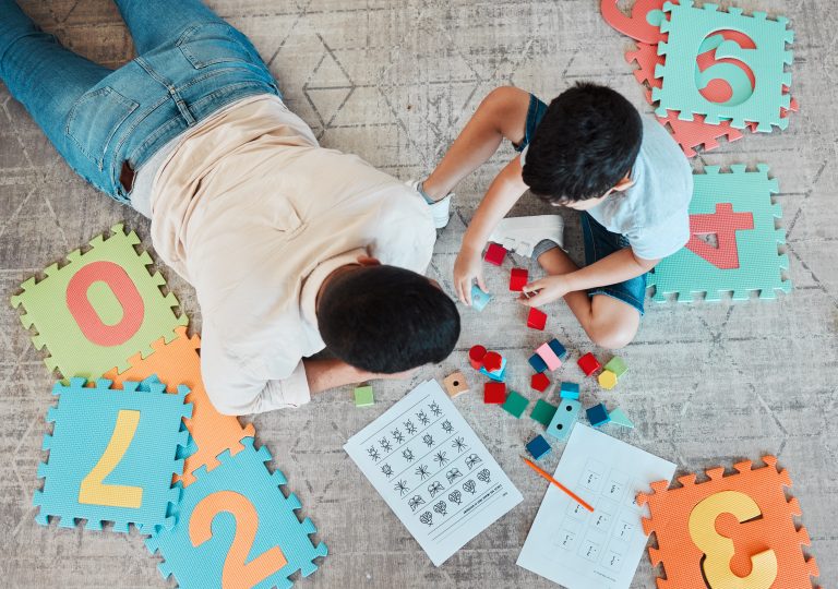 Building blocks, above or father with kid on the floor for learning, education or child development at home. Family, play or dad enjoying bonding time in living room with boy or toys doing homework.